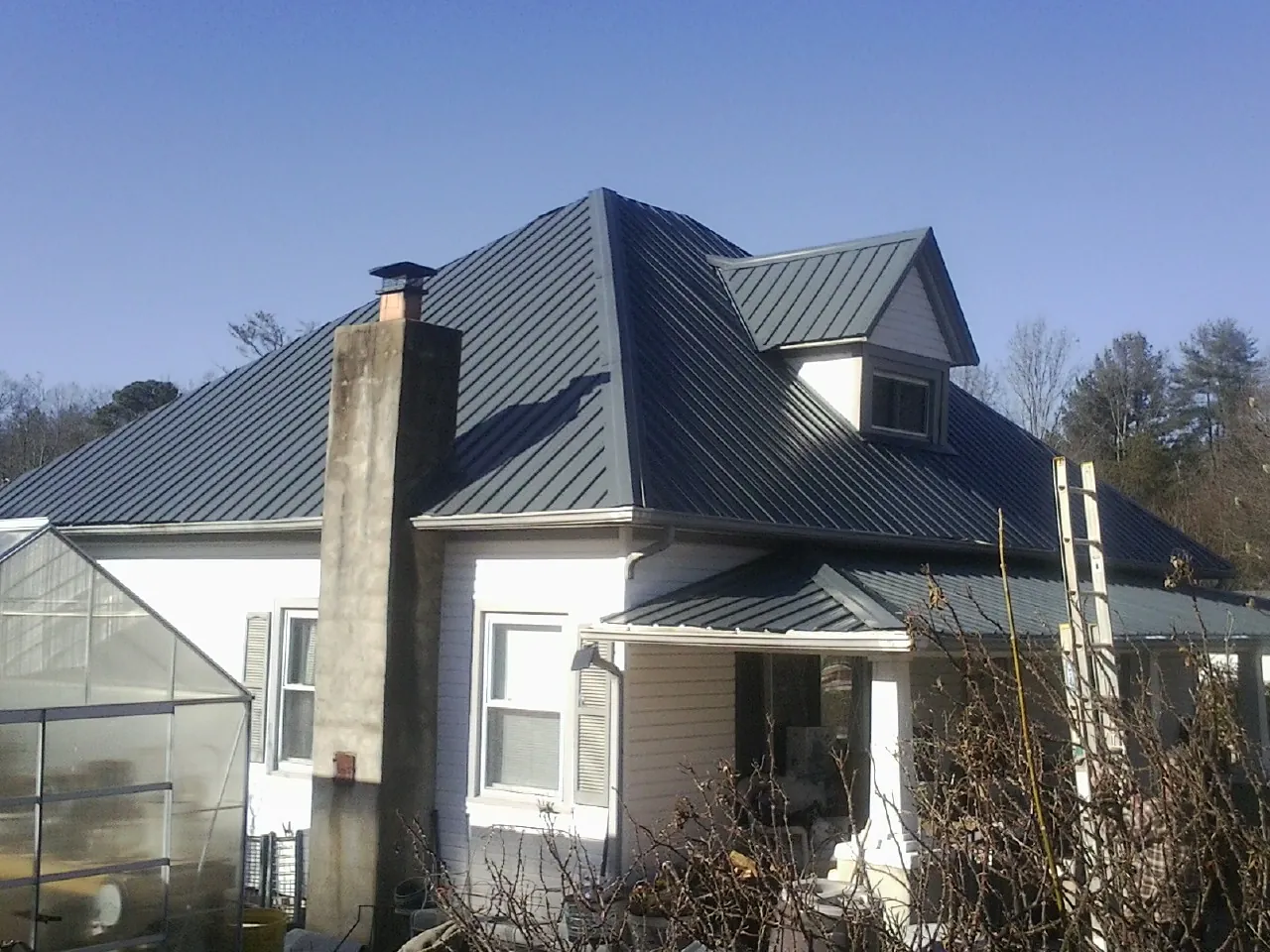 Dark blue standing seam metal roof on a white farmhouse with dormer — Slate & Tile Roof Repair by Roofing Brothers in Duncannon