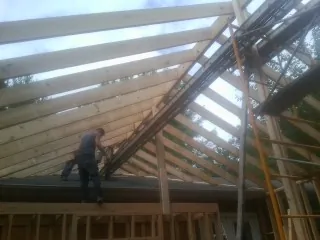 Rafters going up over a new addition with a worker on the wall in Duncannon