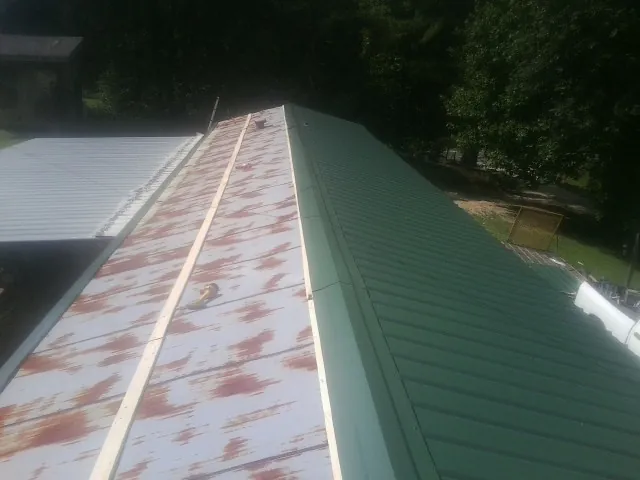 Old rusted panels beside newly installed green metal roofing — Wind Damage Roof Repair by Roofing Brothers in Duncannon