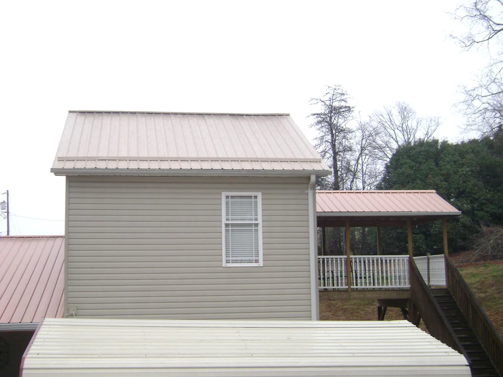 Tan metal roofs on a two story addition and attached porch, from a Roof Replacement job in Duncannon