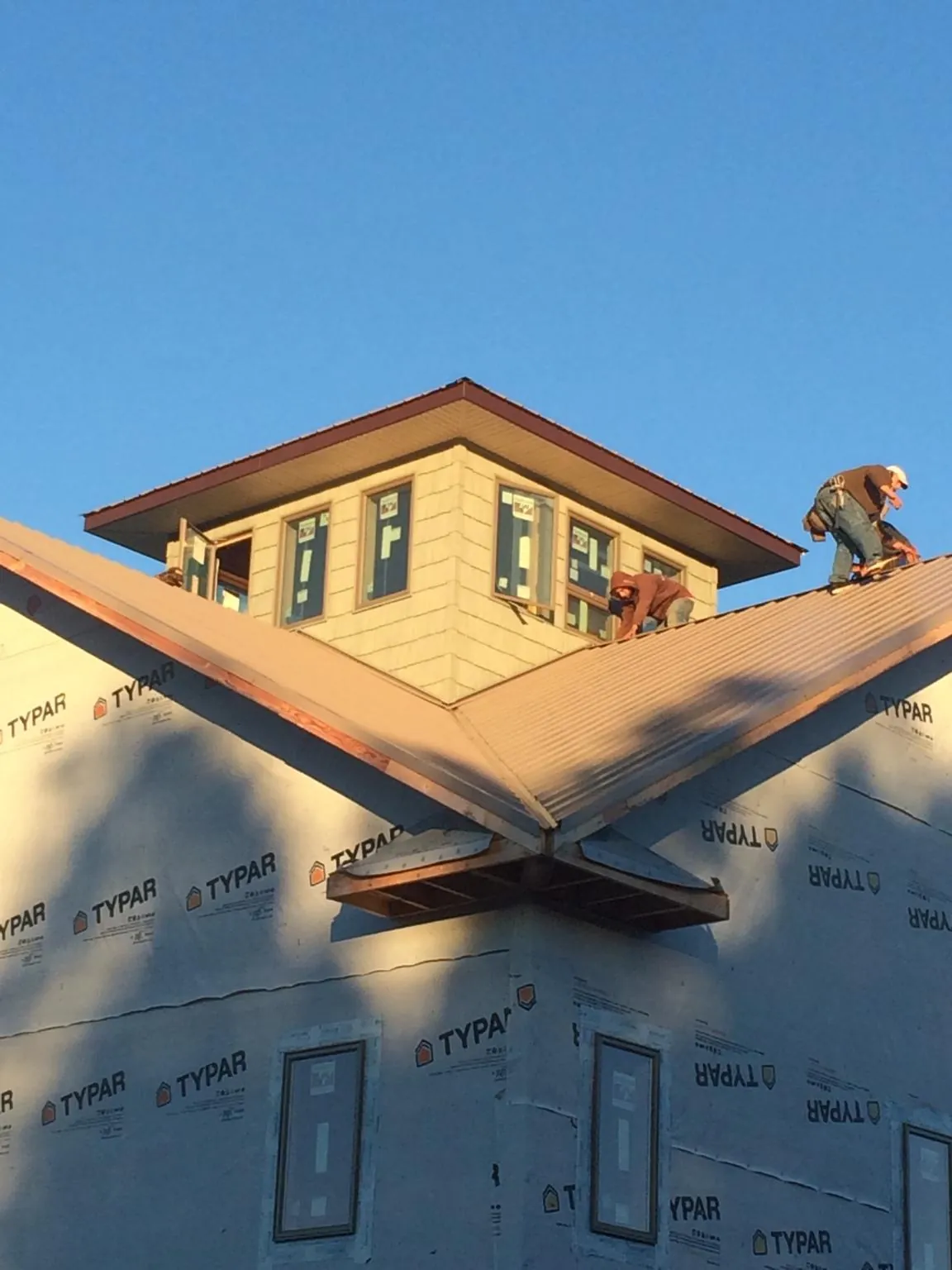 Roofers working around a rooftop cupola on a new metal roof at sunset — Roof Waterproofing in Duncannon by Roofing Brothers